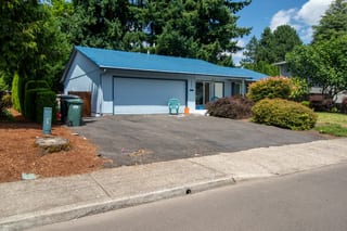 Royal Blue Interlock Shingle aluminum roof on a blue ranch style home with a metal roof among tall trees, Hillsboro, Oregon