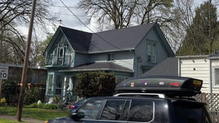 Victorian two-story home in Eugene OR with a steep multi-plane black Interlock aluminum slate metal roof featuring decorative gabled dormers.