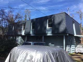 Two-story modern home with deep charcoal Interlock aluminum slate metal roofing, flat-profile upper story, and attached garage in Eugene, OR.
