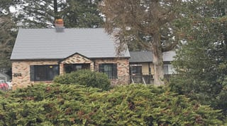 Black Interlock Cedar Shingle aluminum roof on a brown one-storey cottage with a metal roof in a forested, Hood River, Oregon