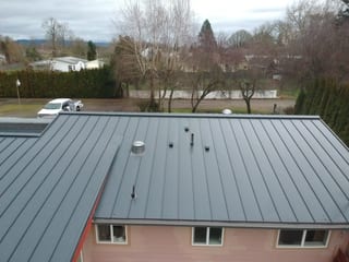 Deep Charcoal Interlock Standing Seam aluminum roof on a pink house with a metal roof in a rural area, Scio, Oregon