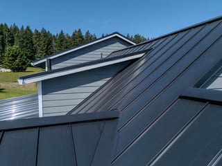 Black Interlock Standing Seam aluminum roof on a black metal roof on a single-storey home in a forested, Warren, Oregon