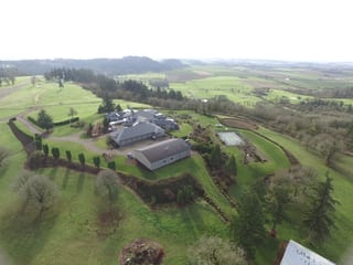 Deep Charcoal Interlock IB Membrane aluminum roof on a two-storey home with a metal roof among tall pines, Turner, Oregon
