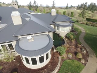 Deep Charcoal Interlock IB Membrane aluminum roof on a two-storey Modern home with a metal roof among trees in a, Turner, Oregon