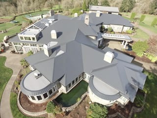 Deep Charcoal Interlock IB Membrane aluminum roof on a white home with a metal roof among trees in a rural, Turner, Oregon