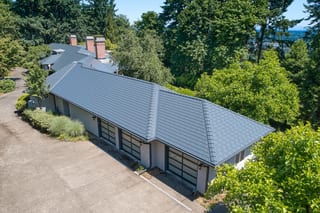 Deep Charcoal Interlock Slate aluminum roof on a two-storey home with dormers among tall trees in a, Portland, Oregon
