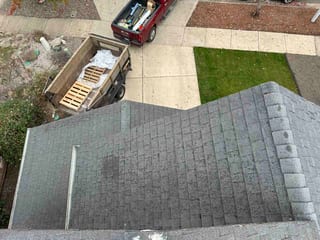 Aerial view of a deep charcoal Interlock aluminum cedar shingle metal roof on a suburban single-family home, showing a multi-plane layout with a valley.