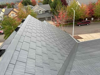 Aerial view of a Craftsman home in Newberg, OR featuring Interlock aluminum cedar shingle roofing in Deep Charcoal with complex hip geometry.