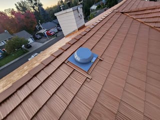 Copper Penny Interlock aluminum shake metal roofing on a steep multi-hip suburban home in Salem, OR, with a roof louver vent and chimney visible.