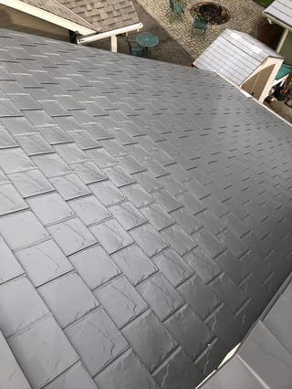 Close aerial view of Interlock aluminum slate roofing in Musket Grey on a residential hip roof in Scappoose, OR, showing wet tile texture detail.