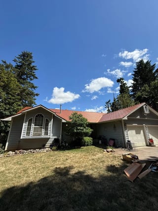 Copper Penny Interlock Slate aluminum roof on a ranch-style home with a brown roof in a wooded area, Corvallis, Oregon