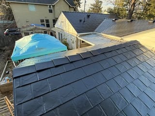 Aerial view of a black Interlock aluminum slate metal roof on a Craftsman-style home in Portland, OR, showing complex multi-plane geometry.