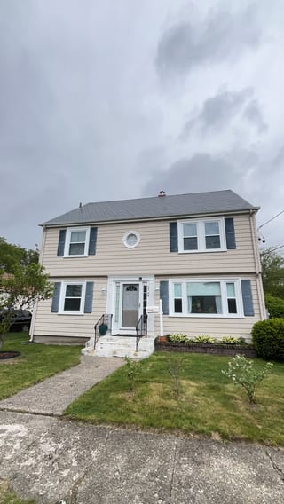 Two-story Colonial home in Pawtucket, RI with Interlock deep charcoal aluminum slate metal roof, dark shutters, and center entry door.