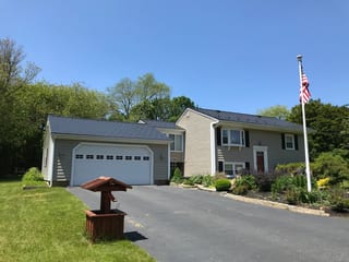 Black Interlock Slate aluminum roof on a beige ranch home with a metal roof in a lush green, Tiverton, Rhode Island
