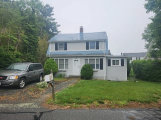 Charcoal Grey Interlock IB Membrane aluminum roof on a grey two-storey Colonial home with dormers among tall, Portsmouth, Rhode Island