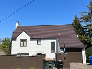 Colonial Brown Interlock Shake aluminum roof on a colonial home with a metal roof among tall evergreens, Seattle, Washington