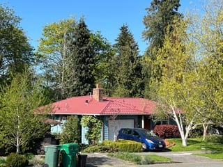 Tile Red Interlock Tile aluminum roof on a house with a red metal roof and a blue car in a suburban, Seattle, Washington