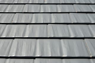 Musket Grey Interlock Cedar Shingle aluminum roof on a grey two-storey home with a modern metal roof among trees, Arlington, Washington