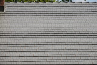 Musket Grey Interlock Cedar Shingle aluminum roof on a grey two-storey home with dormers among tall pines, Arlington, Washington