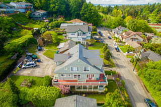Musket Grey Interlock Slate aluminum roof on a grey two-storey home with a metal roof among tall trees, Seattle, Washington