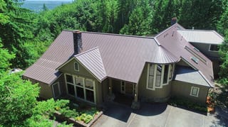 Tudor Brown Interlock Standing Seam aluminum roof on a brown one-storey Tudor home with dormers in the woods, Fall City, Washington