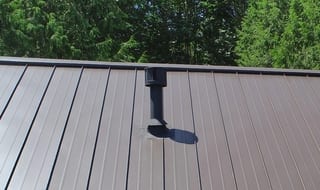 Tudor Brown Interlock Standing Seam aluminum roof on a brown two-storey Tudor home with dormers among tall, Fall City, Washington