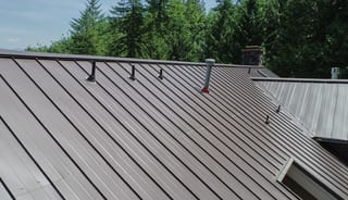 Tudor Brown Interlock Standing Seam aluminum roof on a brown single-storey Tudor home with dormers among tall, Fall City, Washington