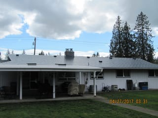 Deep Charcoal Interlock Slate aluminum roof on a white ranch home with a metal roof among tall evergreen, Marysville, Washington