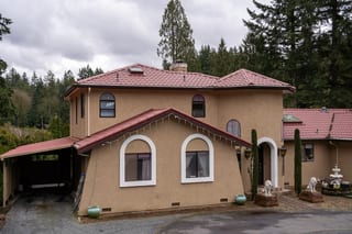 Tile Red Interlock Tile aluminum roof on a tan two-storey home with red tile roof among tall, Woodinville, Washington