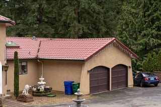 Tile Red Interlock Tile aluminum roof on a tan single-family home with a red tile roof among tall, Woodinville, Washington