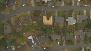 Aged Copper Interlock Cedar Shingle aluminum roof on a beige single-storey home with dormers among green trees, Bellevue, Washington
