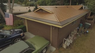Aged Copper Interlock Cedar Shingle aluminum roof on a brown single-family home with a metal roof in a forested, Bellevue, Washington