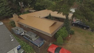 Aged Copper Interlock Cedar Shingle aluminum roof on a two-storey home with a brown metal roof and brick chimney, Bellevue, Washington