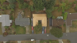 Aged Copper Interlock Cedar Shingle aluminum roof on a tan ranch-style home with a brown roof and a black car in, Bellevue, Washington