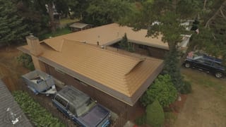 Aged Copper Interlock Cedar Shingle aluminum roof on a brown one-storey home with a chimney and a blue car in a, Bellevue, Washington