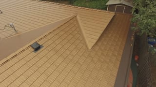 Aged Copper Interlock Cedar Shingle aluminum roof on a two-storey home with a brown metal roof in a forested, Bellevue, Washington
