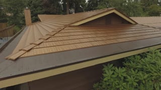 Aged Copper Interlock Cedar Shingle aluminum roof on a brown house with a metal roof among green trees in a, Bellevue, Washington