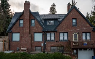 Deep Charcoal Interlock Shake aluminum roof on a red brick craftsman home with a metal roof among tall, Seattle, Washington