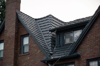 Deep Charcoal Interlock Shake aluminum roof on a red brick home with dark metal roof in a forested urban, Seattle, Washington