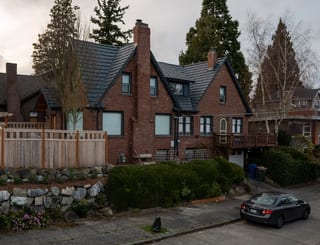 Deep Charcoal Interlock Shake aluminum roof on a brown two-storey Tudor home with dormers among trees, Seattle, Washington