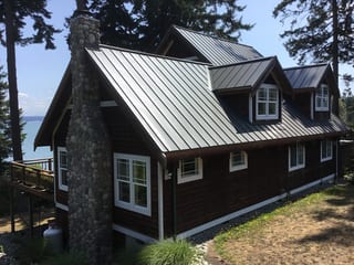 Musket Grey Interlock Standing Seam aluminum roof on a brown two-storey home with dormers near the ocean, Camano Island, Washington