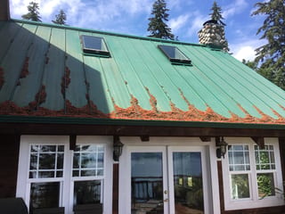 Before: a rusted metal roof on the home, Camano Island, Washington, ahead of a Musket Grey Interlock Standing Seam aluminum roof