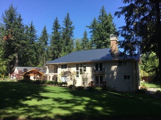 Black Interlock Slate aluminum roof on a white modern home with large windows among tall pines, Bothell, Washington