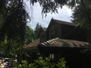 Before: a concrete tile roof with broken tiles on the home, Preston, Washington, ahead of a Hunter Green Interlock Standing Seam aluminum roof