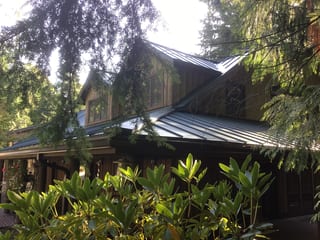 Hunter Green Interlock Standing Seam aluminum roof on a hunter green modern single-family home among tall trees, Preston, Washington