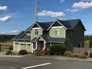 Deep Charcoal Interlock Slate aluminum roof on a green two-storey home with dormers among tall pines, Marysville, Washington