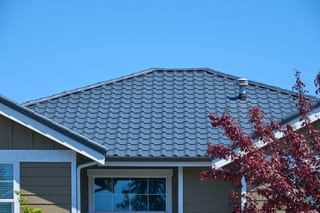 Deep Charcoal Interlock Tile aluminum roof on a two-storey home with a grey roof among tall pines, Lynnwood, Washington