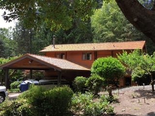 Copper Penny Interlock Shake aluminum roof on a red ranch-style home with a gable roof among trees, Bainbridge Island, Washington