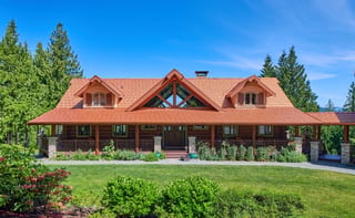 Copper Penny Interlock Shake aluminum roof on a brown one-storey home with dormers on a forested property, Bellingham, Washington