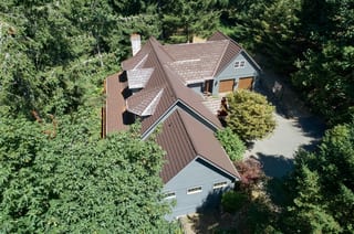 Colonial Brown Interlock Shake aluminum roof on a colonial home with a brown metal roof among tall green, Gig Harbor, Washington